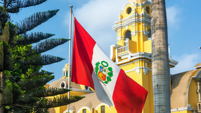 Die peruanische Flagge weht vor der gelben Kirche in Barranco